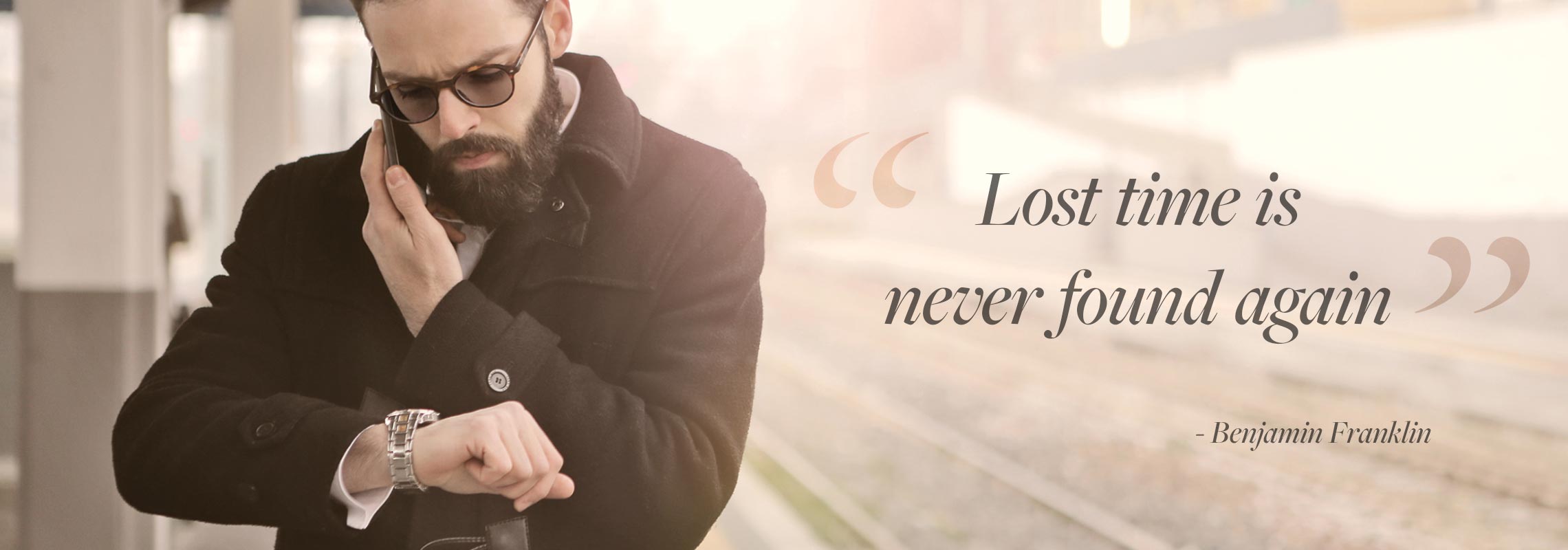 Young hipster man with beard, looking at his watch, wearing glasses with photochromic lenses that get darker in the sunlight