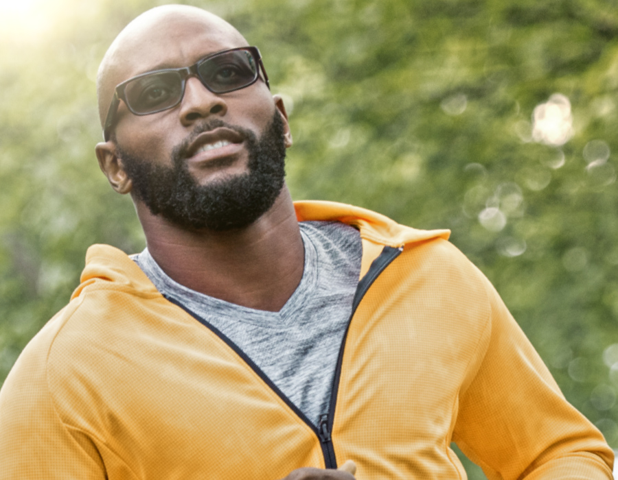 African-American male jogger wearing glasses that have photochromic lenses that get darker in the sunlight